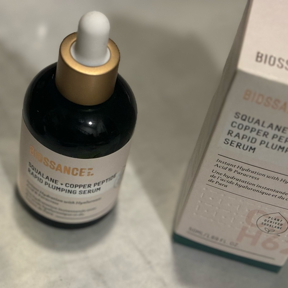 Biossance Gold and White Serum in a Round Glass Bottle